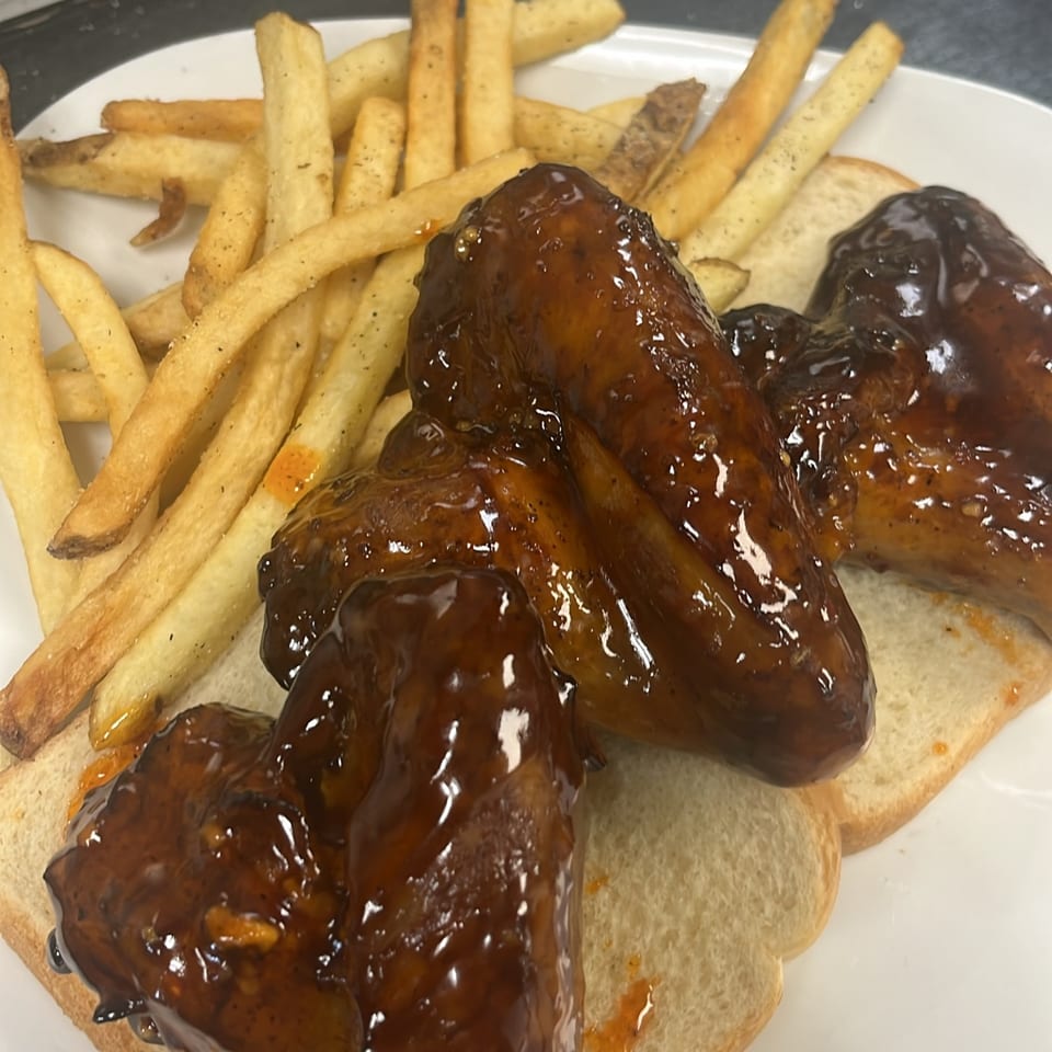 Lutfi’s Raymore's BBQ wings, glistening with sauce, served on white bread with a side of golden fries.